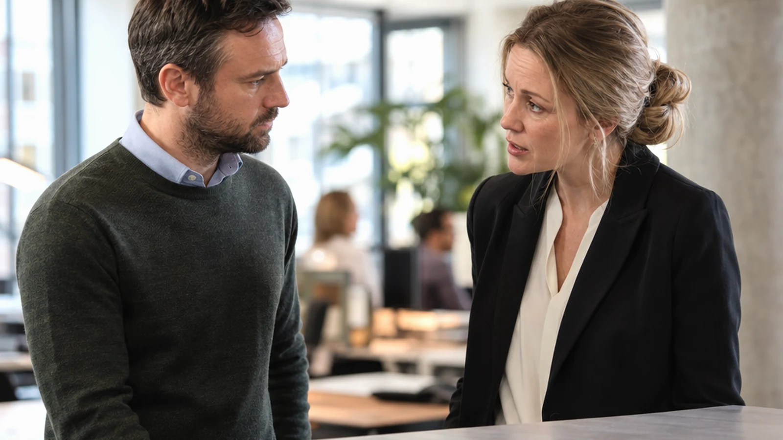 Team members discussing a strained working relationship beside a plain unmarked project surface with no visible writing or branding in an active…